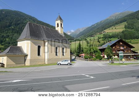 Church And Traditional Chalet At Heiligenblut On Austria