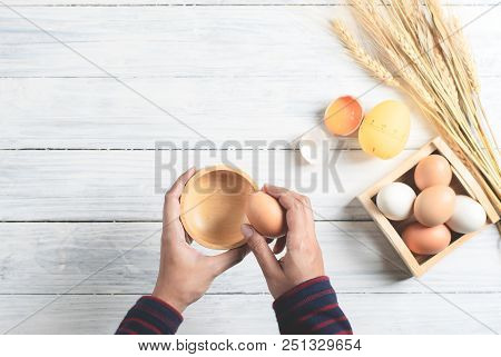 Hands Breaking Boiled Egg With Wood Bowl