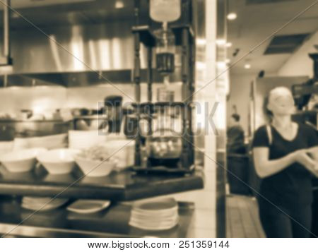 Blurred Background Chef Preparing For Lunch Service And Waitress Taking Ordered Dishes