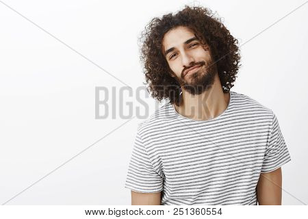 Studio Shot Of Carefree Handsome Confident Eastern Guy With Beard And Afro Hairstyle, Tilting Head A
