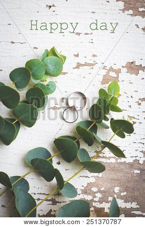 Wedding Rings On A White Old Table With A Sprig Of Eucalyptus, Happy Day