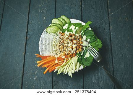Top View Of Buddha Bowl With Vegan Food, Fried Chickpeas, Rice Noodles With Wegetables On Blue Woode