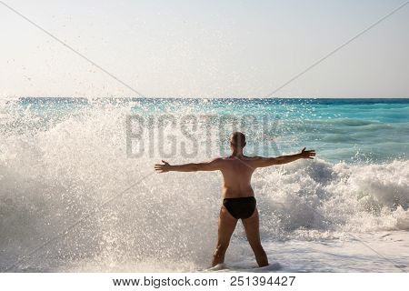 Man Chasing The Waves On Myrtos Beach, Island Kefalonia, Greece