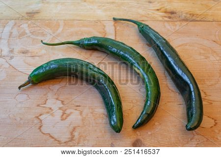 Three Curved Chilaca Peppers Nesting On A Weathered Wood Background, Rustic Food, Horizontal Aspect