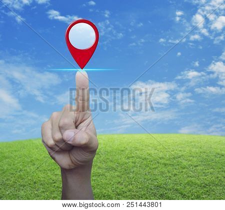 Hand Pressing Map Pin Point Location Button Over Green Grass Field With Blue Sky And White Clouds, M