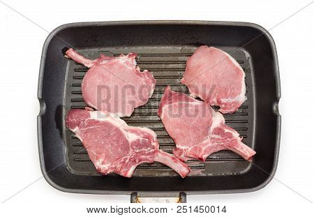 Top View Of The Pork Loin Chops With Partly Frenched Ribs On The Grill Pan During Cooking On A White