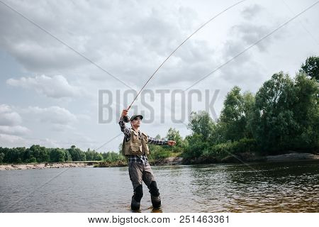 Fisherman Stands In Shallow And Holding Fly Rod Up In One Hand And Part Of Spoon In The Other One. M