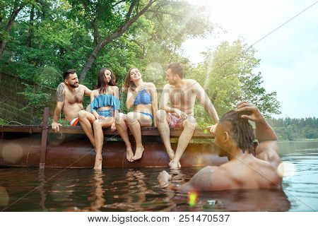 Enjoying Forest Party With Friends. Group Of Beautiful Happy Young Men And Girls Swimming At The Riv