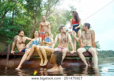 Enjoying Forest Party With Friends. Group Of Beautiful Happy Young Men And Girls Swimming At The Riv