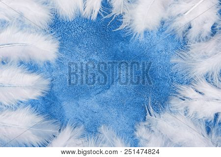Fluffy White Feathers Forming A Frame On A Light Blue Marble Or Concrete Background (as An Abstract 