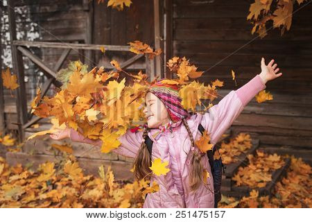 Girl Throws Maple Leaves. Autumn Fun. School Holiday. Child Playing In Leaf Fall.