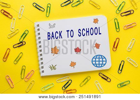 Notebook And Colored Paper Clips On Yellow Background. Back To S