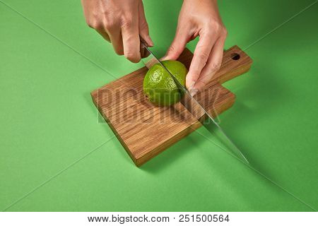 Citrus organic fruits. Female hands cut a juicy green ripe lime to slices for making homemade natural lemonade. Concept of healthy food and drink.