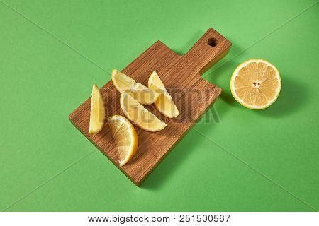 Citrus fruits on a green background with place for text. Top view of slices of natural yellow lemon for preparing homemade lemonade on a wooden board on green.