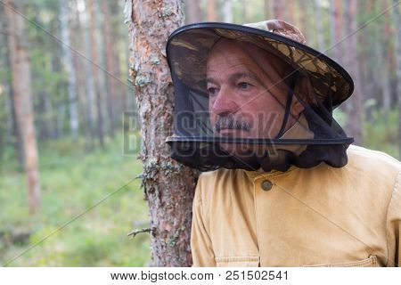 Mature Caucasian Man In Special Anti Mosquito Cap Standing In Forest And Rest While Collecting Mushr