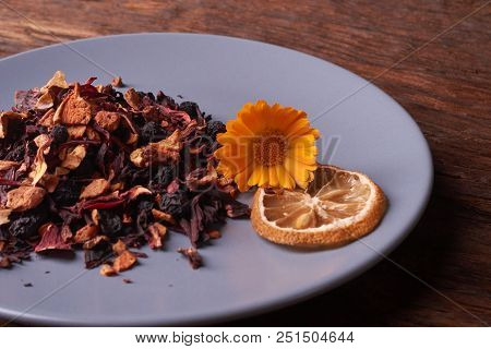 Black Dry Fruit Tea Leaves In Blue Plate On Wooden Table