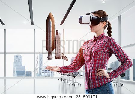 Young Caucasian Woman In Modern Office Interior Trying Virtual Reality Helmet And Viewing Space Shut
