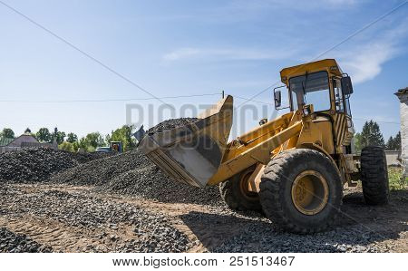 Yellow Loader Moving With Uploaded Bucket To The Truck With Stone Gravel During Road Construction Wo