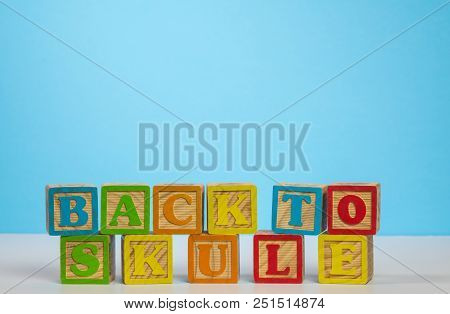 Stack Of Wooden Blocks Wrongly Spelling Back To School As Skule Against Blue Background With Copy Sp