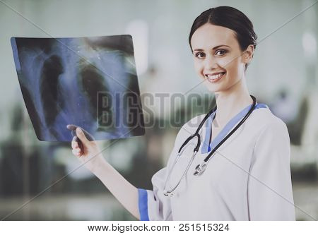 Young Smiling Female Doctor With Stethoscope Looking At X-ray At Doctor Office. Concept Of Health Ca
