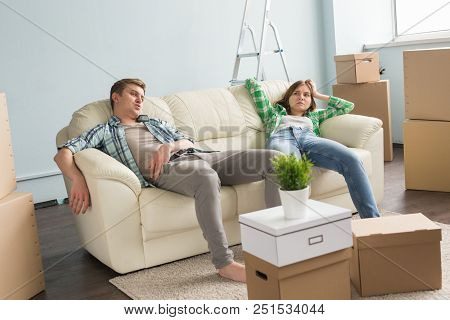 Home, People And Family Concept - Young Cople Having Rest While Moving In A New Apartment.