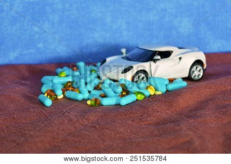 A Child's White Machine Unloads Blue Capsules And Different Tablets On A Brown Surface On A Blue Bac