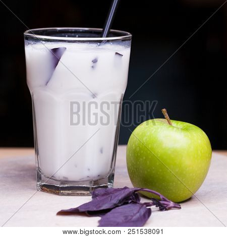 Ayran - liquid drink made from yogurt in ransparent glass cup and green apple