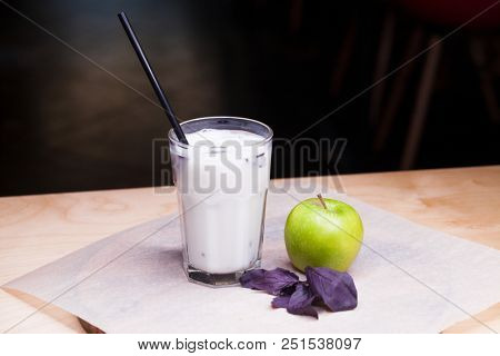 Ayran - liquid drink made from yogurt in ransparent glass cup and green apple