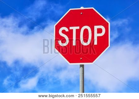 Red Stop Sign Against Blue Cloudy Sky Background. Traffic Regulatory Warning Sign