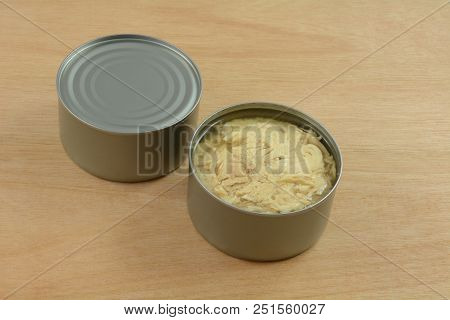 Two Cans Of Albacore Tuna Fish With One Can Opened On Wooden Table
