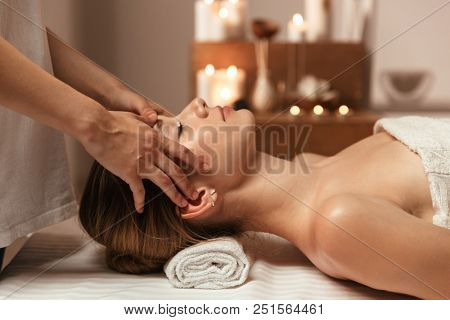 Young woman getting spa treatment with head massage at a spa center