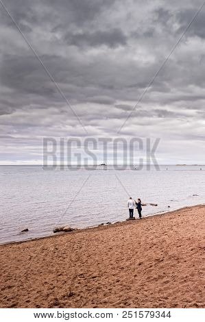 A Couple Is Having A Conversation At The Beach Of Kalajoki, Finland. The People Are Walking On The L