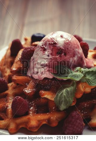 Plate of belgian waffles with ice cream and fresh berries - raspberries and blueberries