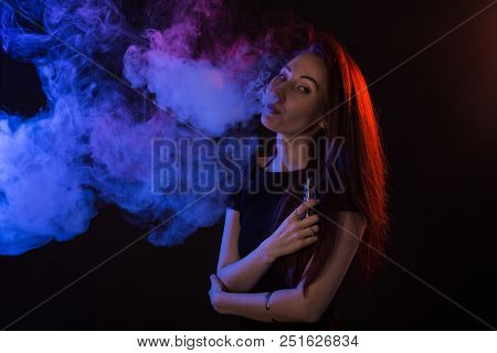 Portrait Of Asian Woman Smoking Vape Or E-cigarette In Neon Light At Black Background