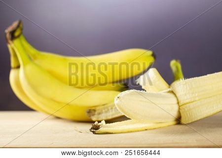Lot Of Whole Fresh Yellow Banana One Cluster And Opened Like A Plane With Grey Gradient Behind