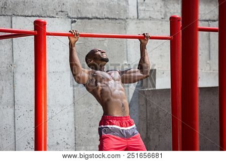 The Fit Athlete Doing Exercises At Stadium. Afro Or African American Man Outdoor At City. Pull Up Sp