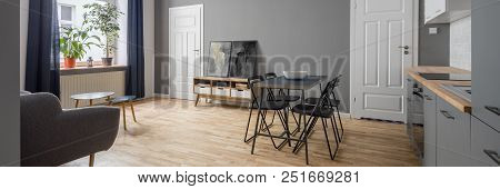 Panorama Of Stylish Open Plan Apartment In Gray With Kitchenette And Simple Table