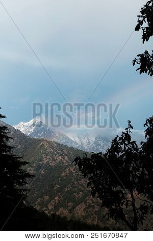 A Vertical Photography Of The Rainbow Against The Background Of Snow-capped Mountains In The Clouds