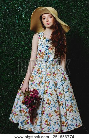 Portrait of a cute girl teenager wearing summer dress and hat over lawny background. Beauty, fashion.