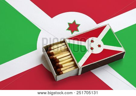 Burundi Flag  Is Shown In An Open Matchbox, Which Is Filled With Matches And Lies On A Large Flag.