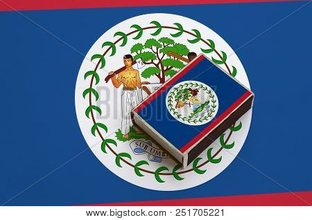 Belize Flag  Is Pictured On A Matchbox That Lies On A Large Flag.