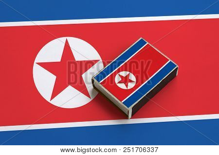 North Korea Flag  Is Pictured On A Matchbox That Lies On A Large Flag.