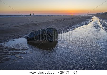 Tow Women Walking By Sea Shore At Sunset. Matalascanas Seascape At Sunset, Huelva, Andalusia, Spain