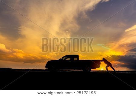 Man Pushing A Broken Car Down The Road.