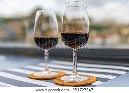 Glasses of port wine at an outdoor restaurant with the Douro river and Dom Luis I bridge blurred in the background in Porto, Portugal