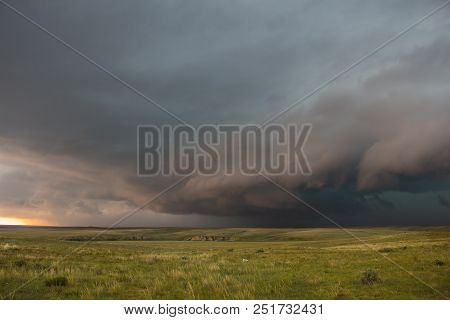 A Severe Thunderstorm Approaches Over The Great Plains Landscape. The Early Evening Sun Casts An Eer