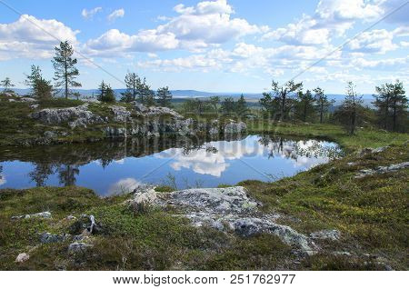 Small Pond On Sarkitunturi Fell Top Reflects The Blue Sky And White Clouds