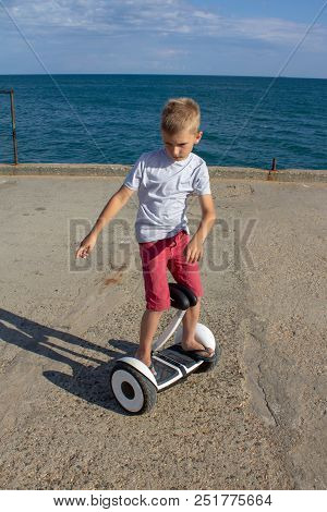 Child On Hover Board. Kids Riding Scooter In Summer Near The Sea. Balance Board For Children. Electr