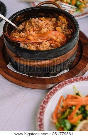 National Cuisine Of Cape Verde: Cachupa With Prawn In Traditional Stone Bowl With Vegetable Salad On