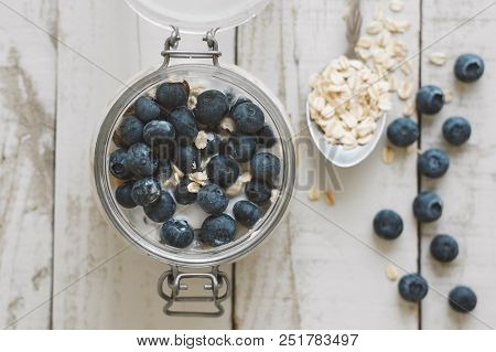 Overnight Oats With Soaked In Coconut Milk With Fresh Bluberry On Wooden Table, Top View. Healthy Br